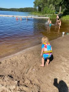 un niño pequeño jugando en la orilla de un lago en Lakeview Studio en Stavsjo