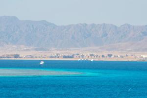 a boat in the water with mountains in the background at Kempinski Hotel Soma Bay in Hurghada