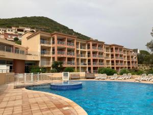 a swimming pool with chairs and a hotel at Appartement VAIANA avec piscine en bord de mer in Ajaccio