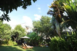 a yard with chairs and an umbrella and trees at iRoHa Garden Hotel & Resort in Phnom Penh