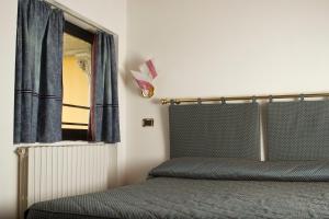 a bedroom with a bed and a window with blue curtains at Hotel Liberty in Spresiano