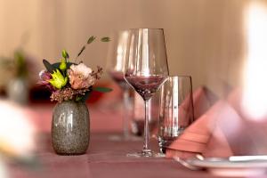 een tafel met twee glazen wijn en een vaas met bloemen bij Tertianum Parkresidenz Meilen in Meilen