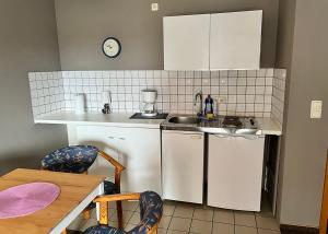 uma pequena cozinha com armários brancos e um lavatório em Hostel Fehmarn Ferienwohnung em Fehmarn