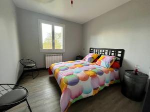1 dormitorio con 1 cama con un edredón colorido en Gîte à l’orée du pré en Villiers-Saint-Benoît