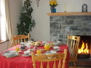 a table with a red table cloth and a fireplace at Mountainview B&B in Leenaun