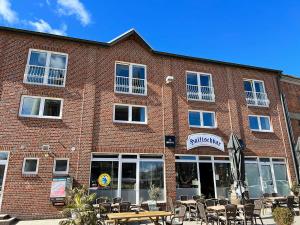 ein Backsteingebäude mit Tischen und Stühlen davor in der Unterkunft Hostel Fehmarn Mehrbett-Zimmer in Fehmarn