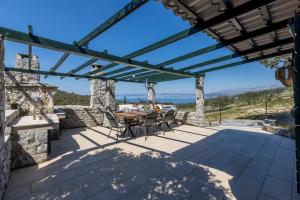 eine Terrasse mit einem Tisch und Stühlen unter einer Pergola in der Unterkunft Vila Scripea in Škrip