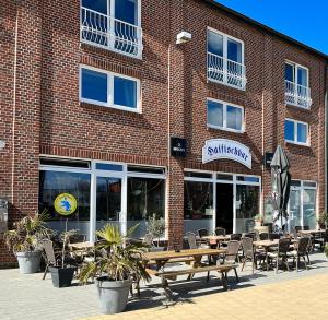a restaurant with tables and chairs in front of a brick building at Hostel Fehmarn Ferienwohnung in Fehmarn