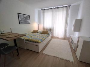 Un dormitorio con una cama y una mesa y una ventana. en Útulný byt s výhľadom na Tatry, en Poprad