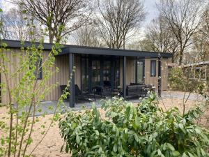 una pequeña casa con techo negro en Vakantiecentrum De Ullingse Bergen, en Sint Anthonis