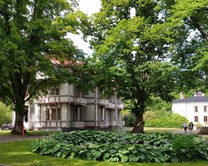 una vecchia casa con alberi di fronte di Villa Eira vandrarhem a Hjo