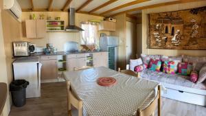 eine Küche und ein Esszimmer mit einem Tisch und einem Sofa in der Unterkunft Châlet dans parc de loisirs 5 étoiles in Puget-sur Argens