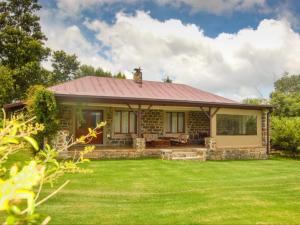 a house with a red roof and a yard at Watersmeet cottages in Dullstroom