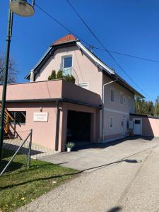 una casa rosa con un garaje en una calle en Ferienwohnung Pichler en Feistritz im Rosental
