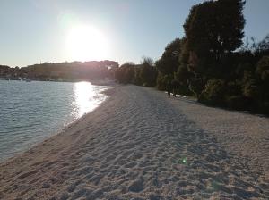 una playa de arena con el sol reflejándose en el agua en Luxury home Alpha, pool, camp Volme - nearby Kamenjak, en Banjole