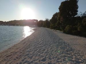 a sandy beach with the sun reflecting on the water at Luxury home Alpha, pool, camp Volme - nearby Kamenjak in Banjole