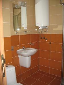 a bathroom with a sink and a toilet and a mirror at Апартаменти Кралеви в Шато Ахелой in Aheloy