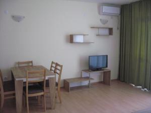 a living room with a table and a television at Апартаменти Кралеви в Шато Ахелой in Aheloy