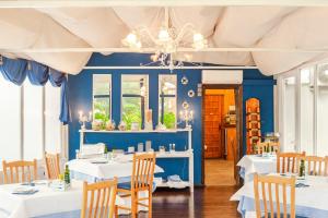 a dining room with blue walls and white tables at Villa La Argentina in Luarca