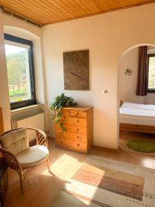 a bedroom with a bed and a chair and a dresser at Ferienwohnung Mila in Obernhof