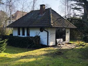 a small white house with a chair in a yard at Bungalow "Prinz" in Nebel