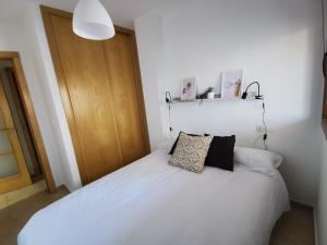 ein Schlafzimmer mit einem weißen Bett mit zwei Kissen darauf in der Unterkunft Precioso apartamento en la playa de la Lanzada. in Sanxenxo