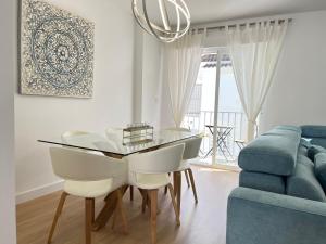 a dining room with a glass table and a blue couch at Casa del olivo in Almuñécar