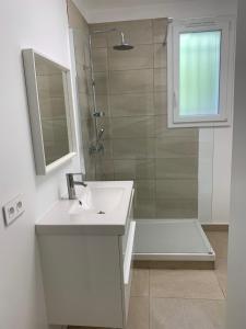 biała łazienka z umywalką i prysznicem w obiekcie Le Rossignol 1, Aiguebelle plage w mieście Le Lavandou