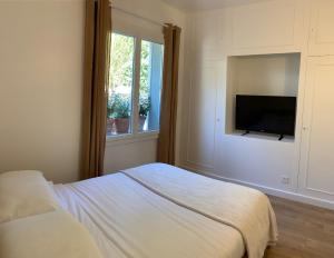 a bedroom with a bed and a flat screen tv at Le Rossignol 1, Aiguebelle plage in Le Lavandou