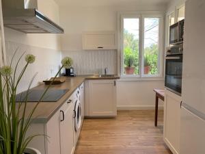 cocina con armarios blancos, fregadero y ventana en Le Rossignol 1, Aiguebelle plage en Le Lavandou