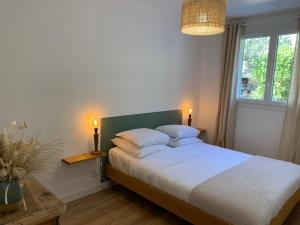 een slaapkamer met een groot bed met 2 kussens bij Le Rossignol 1, Aiguebelle plage in Le Lavandou