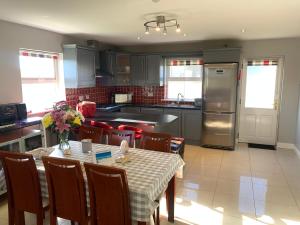 a kitchen with a table with chairs and a refrigerator at Seascape on the edge of town: 4 beds all ensuite. in Belmullet