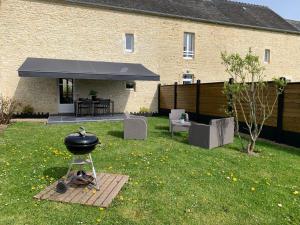 a bbq grill in a yard next to a building at Gîte avec jardin à 1,5 km des plages du débarquement in Tracy-sur-Mer