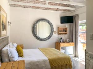 1 dormitorio con cama y espejo en la pared en Seeplaas Guesthouse, en Groot Brak Rivier