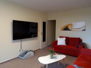 a living room with a red couch and a flat screen tv at Hike & Bike in Altenau