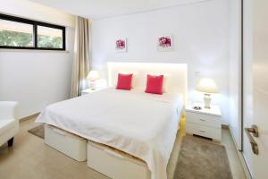 ヴィラモウラにあるMarina Mar Vilamoura Apartmentの白いベッドルーム(大型ベッド1台、赤い枕2つ付)
