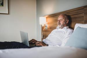 a man laying in bed using a laptop computer at Hotel Atlantic in Aarhus