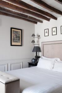 una camera con un letto bianco e un tavolo di Hotel Saint-Louis en L'Isle - Notre-Dame a Parigi