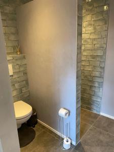 a bathroom with a toilet and a brick wall at De Veluwse bos Lodge in Otterlo