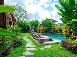 een achtertuin met een zwembad en een groep banken bij Pondok Naya - CHSE Certified in Ubud