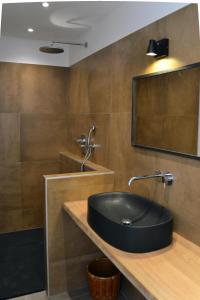 baño con lavabo negro y espejo en Les Chêneslierres, en Lourmarin