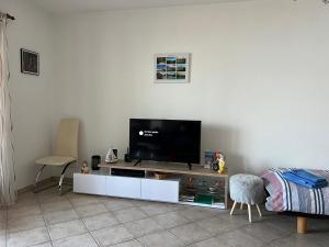 een woonkamer met een flatscreen-tv op een wit entertainmentcentrum bij 1 Zimmer Apartment mit Seesicht und Pool in Vira