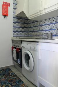 een wasmachine en droger in een keuken met een muur bij Óasis - Pedras D' El Rei T0 in Santa Luzia