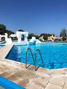 een zwembad met blauw water in een resort bij Óasis - Pedras D' El Rei T0 in Santa Luzia