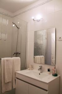 een witte badkamer met een wastafel en een spiegel bij Óasis - Pedras D' El Rei T0 in Santa Luzia