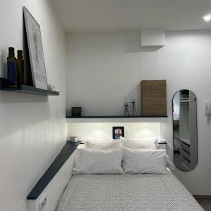 a bedroom with a bed with white sheets and a mirror at MRTN APARTMENTS Studio & Suites - Aix-les-Bains, hypercentre in Aix-les-Bains