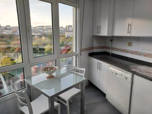 a kitchen with a table and chairs and windows at Apartamento Calzada Romana in Lugo