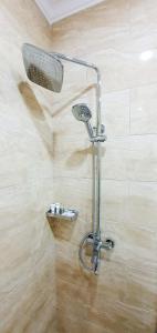 a shower with a shower head in a bathroom at Grand Holiday Hall in Pavlodar