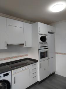 een witte keuken met witte kasten en apparaten bij Apartamento Calzada Romana in Lugo