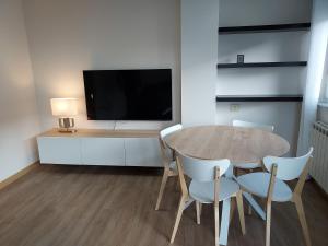 a dining room with a table and chairs and a tv at Apartamento Calzada Romana in Lugo